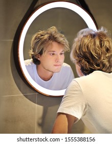 young man looking in the mirror,looking at problems on face
