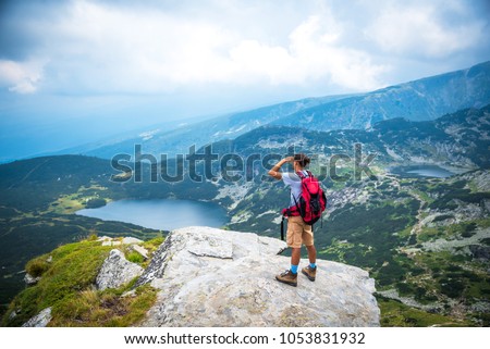 Young man looking at a mountain lake. Hiker in the Seven Rila lakes, Bulgaria. Wanderlust concept