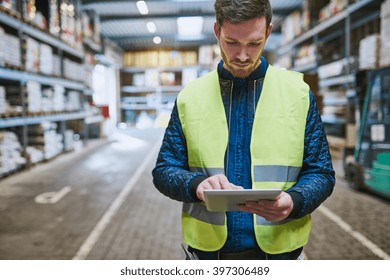 Young man looking up order details on a tablet as he shops in a hardware warehouse for supplies , close up upper body - Powered by Shutterstock