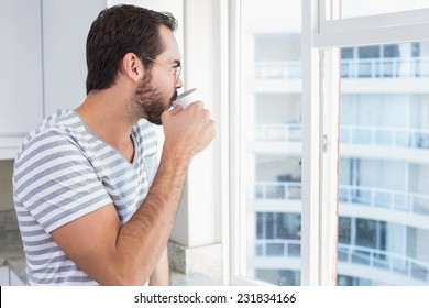 Young man looking out his window at home in the kitchen - Powered by Shutterstock