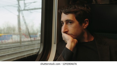 Young Man Looking Out Window While Riding And Commuting By Train