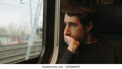 Young Man Looking Out Window While Riding And Commuting By Train