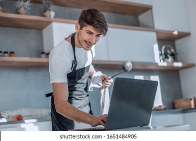 young man looking at recipe in laptop while cooking dinner - Powered by Shutterstock