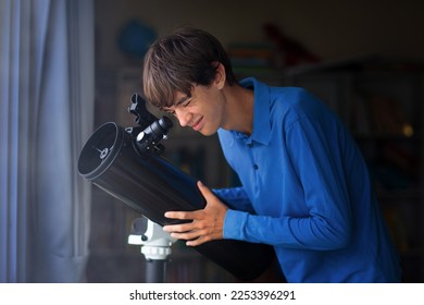Young man looking at stars through telescope. Teenager watching night sky. Teen boy observing planets and moon. Astronomy hobby. Student learning about galaxy. Modern digital device to study space.