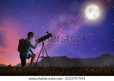 Young man looking at stars through telescope. Camping and hiking fun. Outdoor astronomy hobby. Teenager watching night sky with milky way. Teen observing planets and moon. Nature exploration.