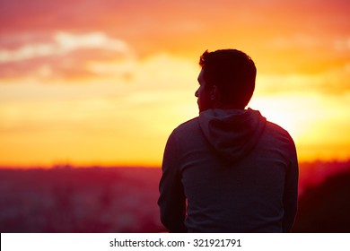 Young man is looking at the sunrise.