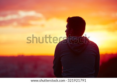 Young man is looking at the sunrise.