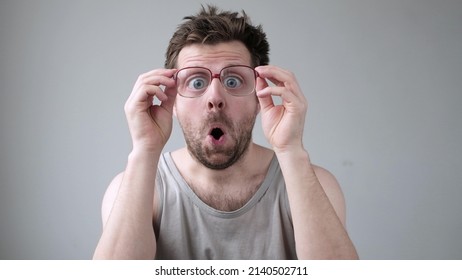 Young man looking through huge glasses in shock with surprise expression.
