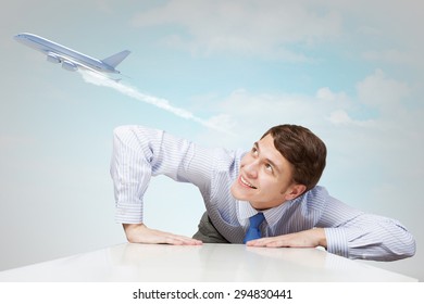 Young Man Looking From Under Table On Flying Airplane