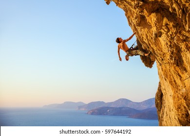Young man looking up while climbing challenging route on cliff - Shutterstock ID 597644192