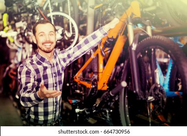 Young man looks at bicycle frame in sports store - Shutterstock ID 664730956
