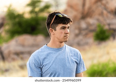 Young man looks thoughtfully into the distance at a rocky outdoor setting during late afternoon - Powered by Shutterstock