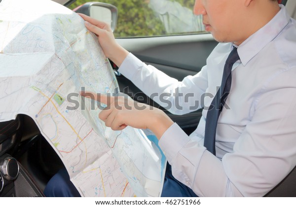 Young man lost direction and looking at map in\
car to plan his journey