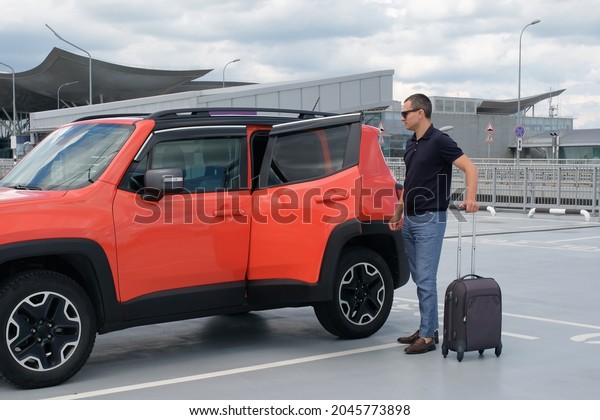 Young man with luggage standing by the car in
the parking.