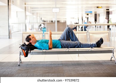 young man lying on airport chairs and resting