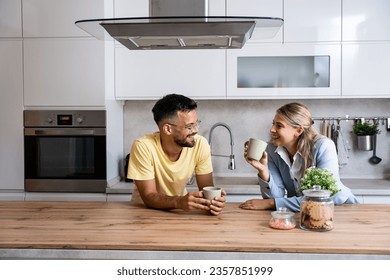 Young man made first coffee for his girlfriend in formal wear who goes to work and they drink it together in the morning in the kitchen while discussing what they will do when she comes home from work - Powered by Shutterstock