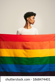 Young Man With Make Up And Earring Standing Behind Gay Pride Flag. Transgender Man Behind Lgbtq Flag.