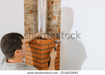 A young man makes brickwork on the chimney of a fireplace.