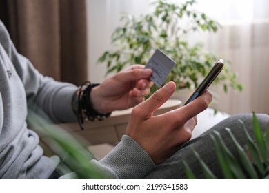 Young Man Makes Shopping Online On A Smartphone, Sends An Online Payment With A Credit Card. Close-up Of Male Hands With Phone And Credit Card