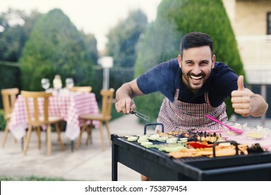 Young man making barbecue at his backyard, thumb up