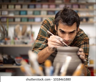 Young man making and decorating pottery in workshop - Powered by Shutterstock