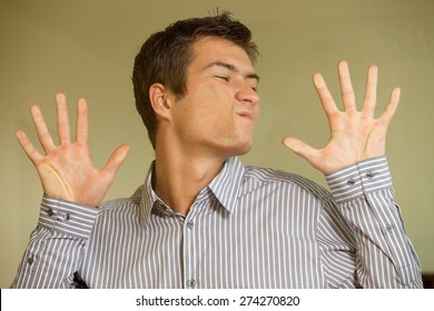 Young Man Making Face On Glass Wall