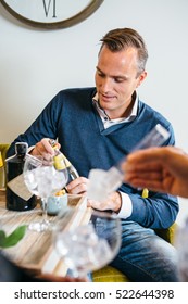 Young Man Making Gin Tonic Cocktails At Party With Friends. 