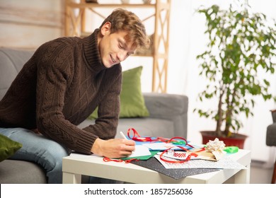 Young Man Making Greeting Card For New Year And Christmas 2021 For Friends Or Family, Scrap Booking, DIY. Writing A Letter With Best Wishes, Design His Homemade Card. Holidays, Celebration.