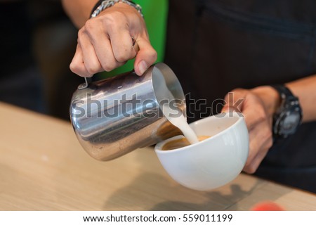 Young man making latte in coffee