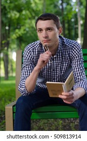 Young man making notes in the notepad on the street