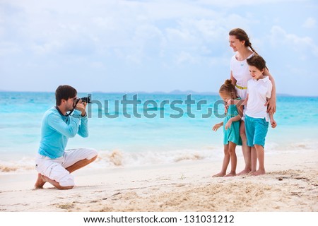 Young man making photo of his wife and kids at tropical beach