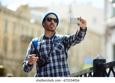 Young man making selfie while having walk in the city