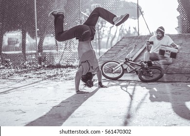 Young man making video of rasta breakdancing perfoming in city park - Hip hop style people having fun  - Focus on left guy - Warm matte filter - Black and white editing - Powered by Shutterstock