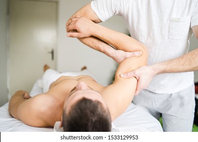 Young man male athlete having sport massage at spa or home by professional therapist relax body recovery healing injury shoulder chiropractics arm