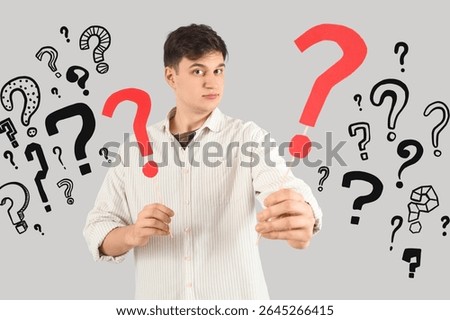 Young man with many question marks on grey background