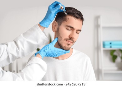 Young man with marked forehead receiving serum for hair growth at hospital, closeup - Powered by Shutterstock