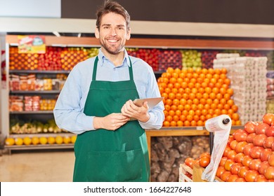 Young man as a market leader with tablet PC in the vegetable section in the supermarket - Powered by Shutterstock