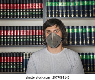 Young Man With A Mask Standing In Front Of A Shelf Full With Law Books