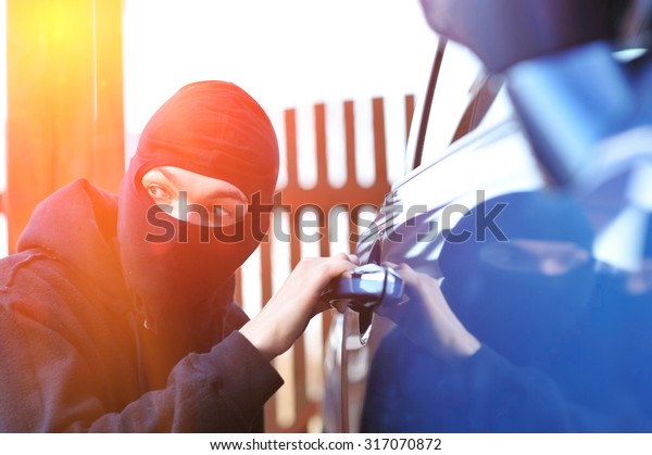 Young man in mask\
trying to steal a car