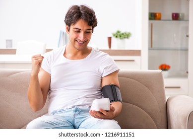 Young Man Measuring Blood Pressure At Home