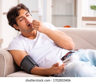 Young Man Measuring Blood Pressure At Home