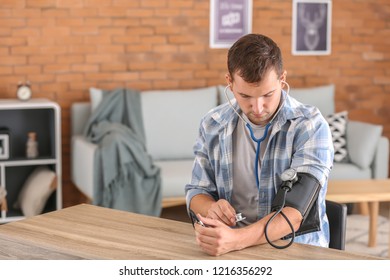 Young Man Measuring His Blood Pressure At Home