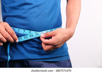 Young Man Measuring His Waist With A Tape Measure, Close Up.