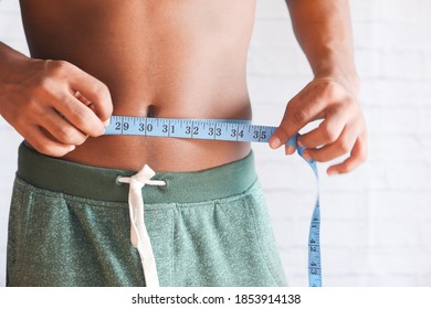 Young Man Measuring His Waist With A Tape Measure, Close Up.