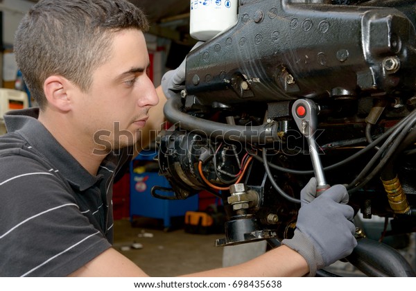 A\
young man mechanic repairing  motor boats and\
other