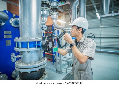 Young Man Mechanical Engineer Control Valves Open - Closed To Checking And Inspection Of HVAC Heating Ventilation Air Conditioning System On Valves Gauge Of Industrial Air Compressor Boiler Pump Room 