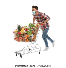 Young Man In Medical Mask With Shopping Cart Full Of Groceries On White Background