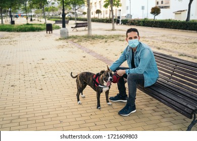 Young man in medical mask sitting on a bench in the park with his dog. Covid-19 coronavirus pandemic. Active quarantine life in the Corona outbreak. - Powered by Shutterstock