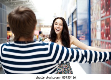 Young Man Meeting His Girlfriend With Opened Arms At Airport Arrival Hall