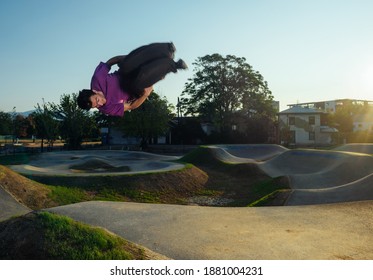 Young man in midair while performing a side flip at the skate park